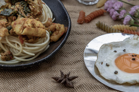 Spaghetti topped with Stir fried spicy snapper on a brown plate Served with Fried Egg. Selective Focus.の写真素材