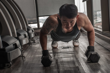 Bangkok, Thailand 06 Oct 2019 : Handsome muscular man doing pushups on dumbbell in gym or fitness...