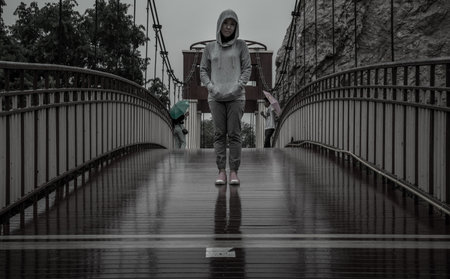 Young asian woman standing on a Wood bridge walkway over the swamps on a rainy day.の写真素材