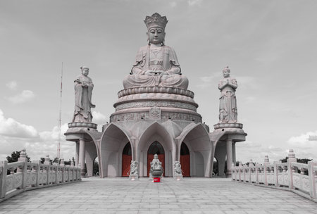 Bangkok, Thailand - 18 Oct, 2025 - A large white marble statue of Guanyin of the Goddess of Mercy. It is seated on a celestial platform and is surrounded by smaller statues against a clear blue sky at the Guanyin Bodhisattva's Hall in Bangkok, Selective focus.の写真素材