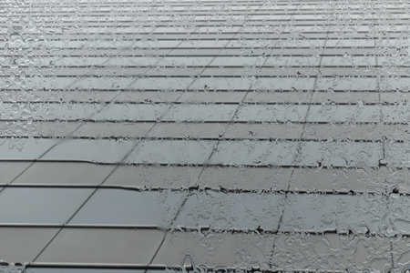 Looking up from below, the glass surface shines with raindrops streaming down its surface. Raindrops...