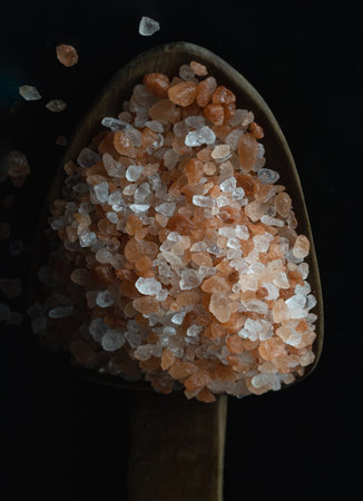 View of Pink Himalayan Salt with Bright colors textured surface on Wooden scoop with the dark...