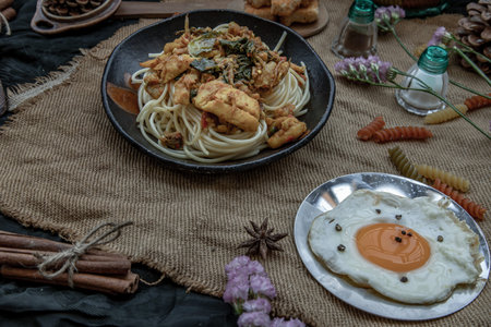 Spaghetti topped with Stir fried spicy snapper on a brown plate Served with Fried Egg. Selective...