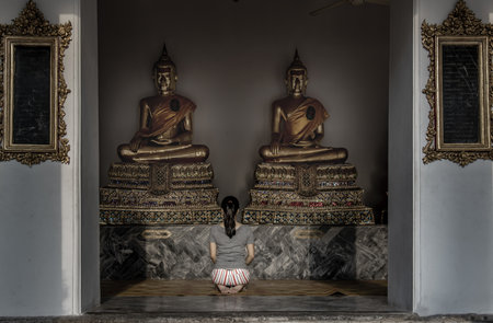 Bangkok, Thailand 27 Oct, 2019 : Young woman sitting praying pay respect to Buddha statue in the Wat Phra Chetuphon Wimon Mangkhalaram Ratchaworamahawihan. Worship pray.のeditorial素材