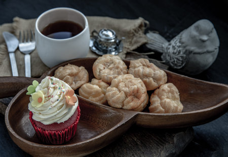 Breakfast time . Choux cream with cupcake and tea on wooden background. Oblique view from the top.