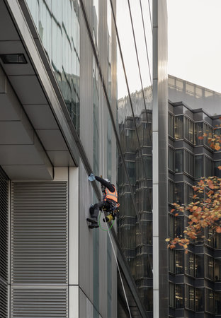 London, UK - Nov 07, 2023 - Suspended by high-tension ropes, a worker in safety gear maneuvers down...
