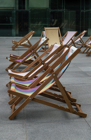 London, UK - Jun 09, 2025 - The Wooden deck chairs are arranged in a diagonal recession, creating...