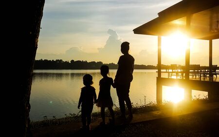 Lady and children stand by the lake in the eveningの写真素材