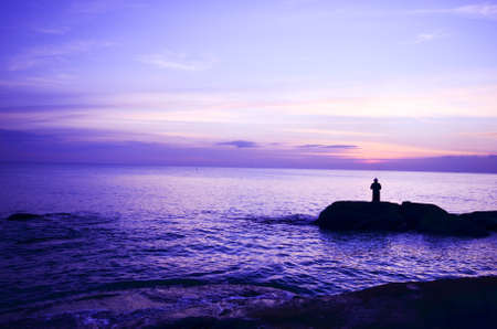 Fisherman fishing on a beach alone before sunsetの写真素材