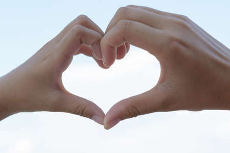 clasped hands forming a heart with natural backgroundの写真素材