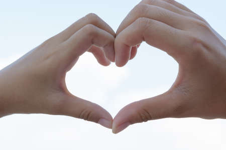 clasped hands forming a heart with natural backgroundの写真素材