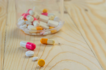 Medicine tablets and white plastic bottle on a wooden backgroundの写真素材