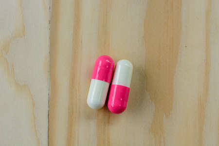Medicine tablets and white plastic bottle on a wooden backgroundの写真素材