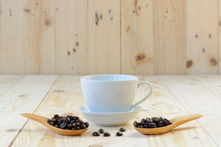 a cup of coffee and coffee beans in spoon on wooden tableの写真素材