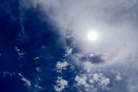 Sun corona on blue sky with cloudsの写真素材