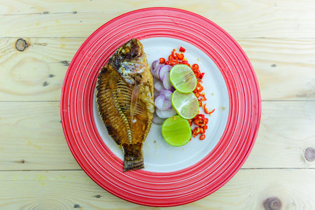 Delicious fried Tilapia fish with lemon and onion rings arranged in a plate