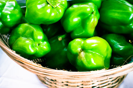 Group of green bell peppers on a wicker basket.の写真素材