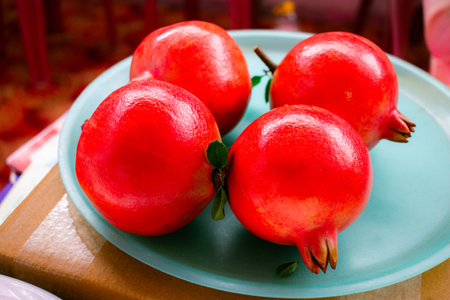 Heap of fresh shiny pomegranates on a plastic plate.の写真素材