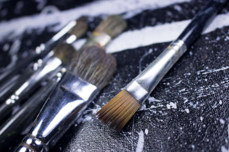 paint brush on grungy black and white acrylic paint canvasの写真素材
