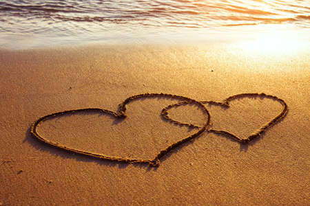 honeymoon or valentine s day greetings on the sand, two heartsの写真素材