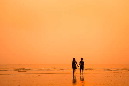 sunset silhouettes of loving couple on the beach の写真素材