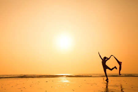 dancing woman at sunset on the beachの写真素材