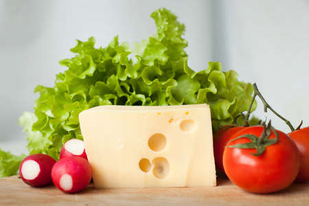 cheese and vegetables for salad on wooden board in the kitchenの写真素材