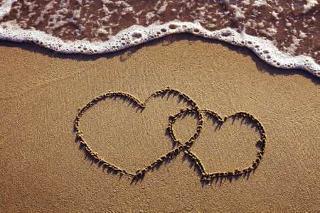 honeymoon or valentine's day greetings on the sand, two heartsの写真素材