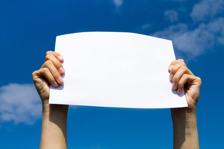blank page in hands on blue sky backgroundの写真素材