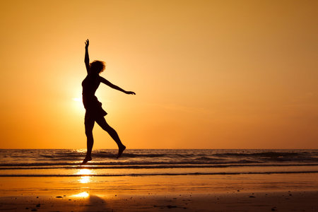silhouette of happy woman jumping on the beach, healthy lifestyleの写真素材
