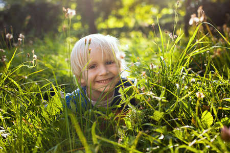 blond happy little boy in the grassの写真素材