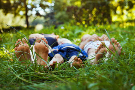group of happy children lying on green grass outdoors, familyの写真素材