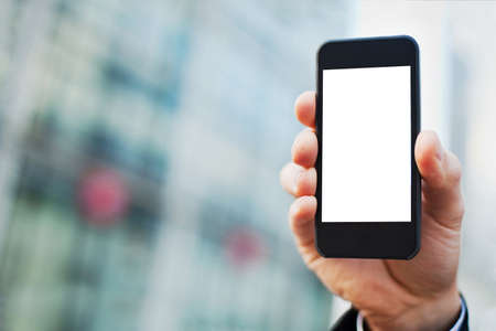 hand of business man with smartphone on office buildings backgroundの写真素材