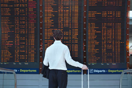 passenger looking at timetable board at the airportの写真素材