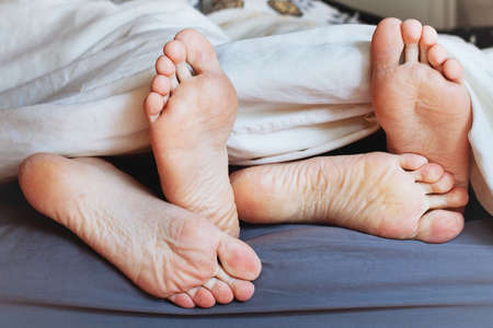 feet of family under blanket, happy morning of loving coupleの写真素材