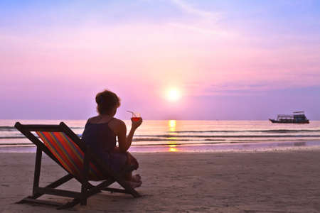 middle age woman with cocktail enjoy sunset on the beachの写真素材