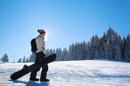 silhouette of woman with snowboard on the ski slopeの写真素材