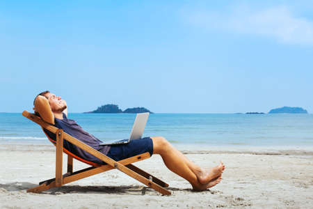 smiling businessman with computer relaxing on the beach smiling businessman with computer relaxing on the beach