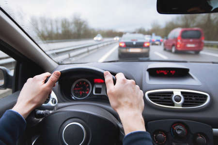 driving car on highway, close up of hands on steering wheelの写真素材