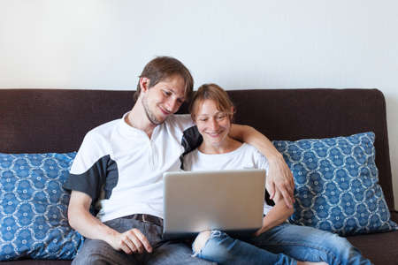 happy smiling couple with laptop at home, shopping onlineの写真素材