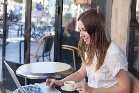 smiling young woman with computer in cafeの写真素材