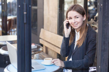 smiling business woman talking by phone in cafeの写真素材