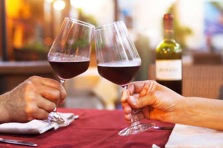 couple drinking wine in restaurant, close up of hands with glasses, happy momentの写真素材