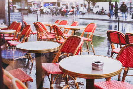 street cafe in Paris in rainy day, red wicker chairs and tablesの写真素材