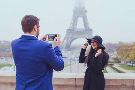 mobile photography, man taking photo of woman with his phone, couple of tourists near Eiffel Tower in Paris, Franceの写真素材