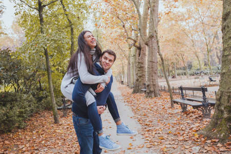 happy young couple having fun in autumn park, caucasian family, man and woman, piggybackの写真素材