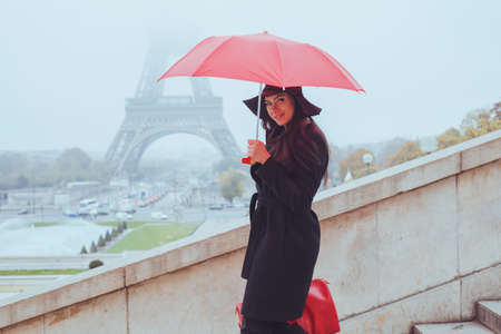 cold weather in Paris, portrait of fashion woman with red umbrella and bag near Eiffel Tower, winter shopping in Europeの写真素材