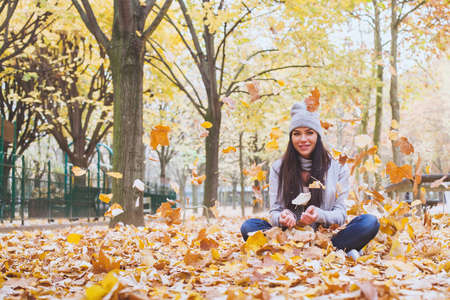 autumn park, beautiful smiling woman and falling yellow leavesの写真素材
