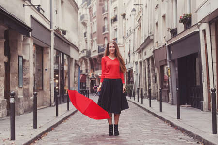 beautiful woman, portrait of girl with red umbrella standing on the street of Parisの写真素材