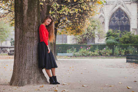 portrait of beautiful young woman, blond model with long hair posing in red blouse and black skirt, photoshoot in Parisの写真素材